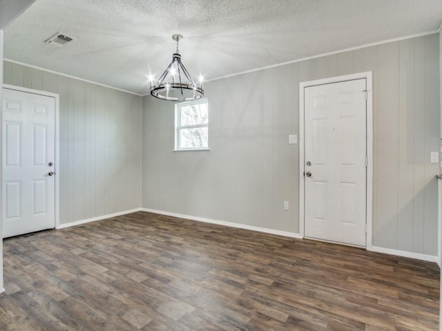 unfurnished dining area featuring crown molding, dark hardwood / wood-style floors, a notable chandelier, and a textured ceiling