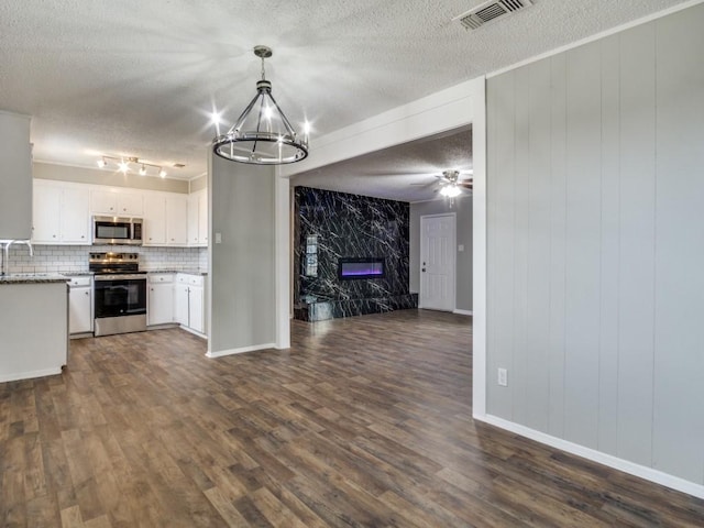 kitchen featuring a premium fireplace, appliances with stainless steel finishes, white cabinetry, a textured ceiling, and decorative backsplash