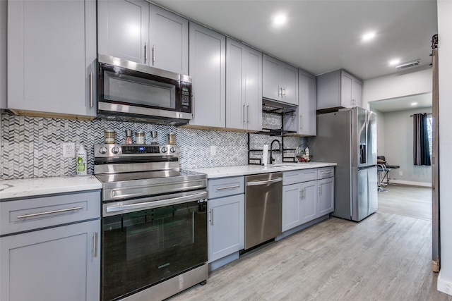 kitchen featuring appliances with stainless steel finishes, gray cabinets, and light hardwood / wood-style flooring