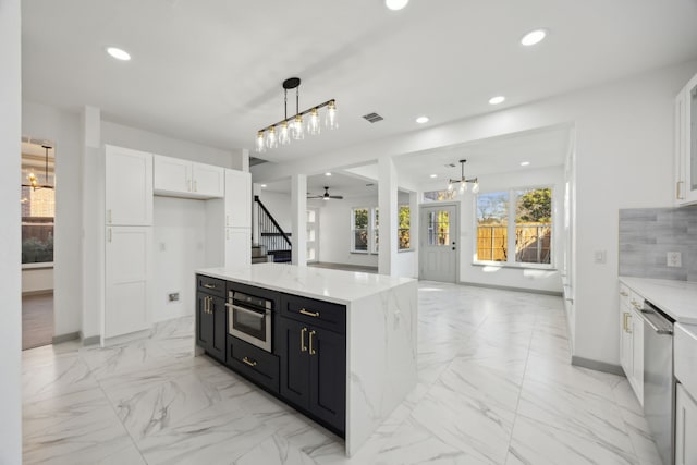 kitchen featuring hanging light fixtures, white cabinetry, a kitchen island, and stainless steel appliances