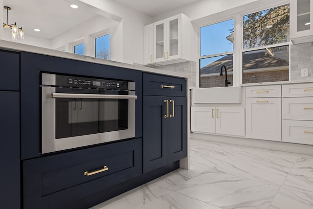 kitchen with white cabinetry, pendant lighting, sink, and stainless steel oven