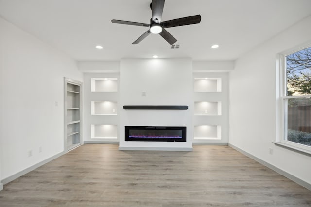 unfurnished living room with ceiling fan, built in features, and light hardwood / wood-style floors