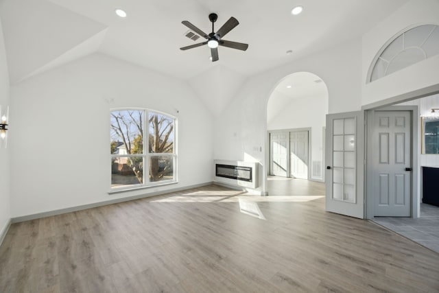 unfurnished living room with heating unit, vaulted ceiling, ceiling fan, and light hardwood / wood-style flooring