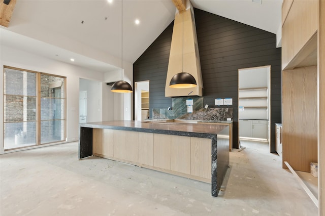 kitchen featuring pendant lighting, light brown cabinetry, wooden walls, and high vaulted ceiling