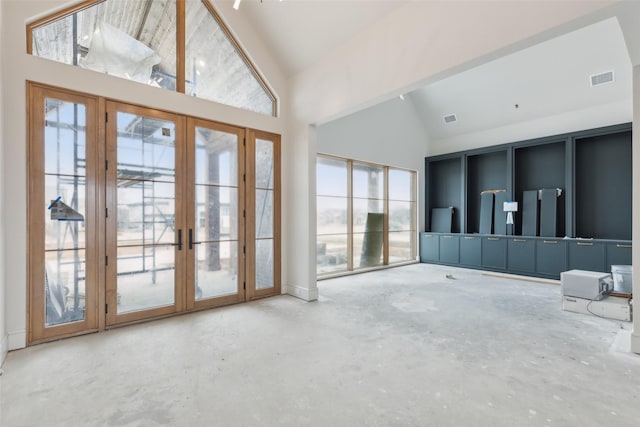 interior space with french doors, high vaulted ceiling, and concrete floors