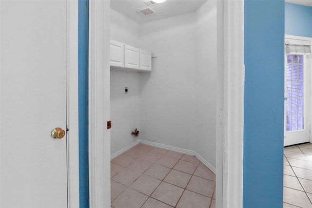 laundry room featuring electric dryer hookup, cabinets, and light tile patterned flooring