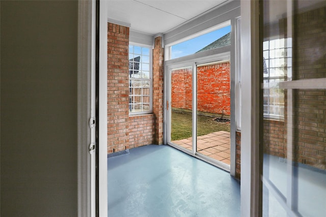 doorway to outside with concrete flooring and brick wall