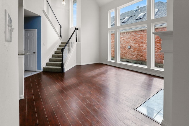 unfurnished living room featuring wood-type flooring and a towering ceiling