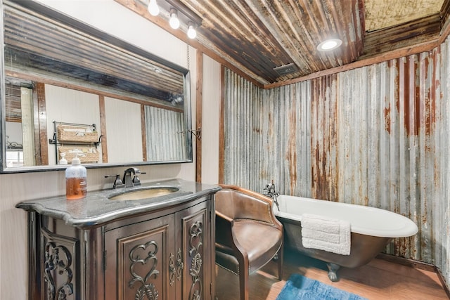 bathroom featuring hardwood / wood-style flooring, a tub to relax in, vanity, and wooden ceiling