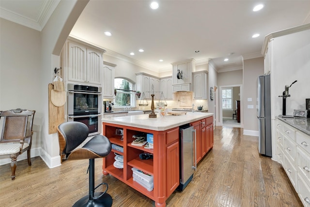 kitchen with plenty of natural light, beverage cooler, white cabinets, and appliances with stainless steel finishes