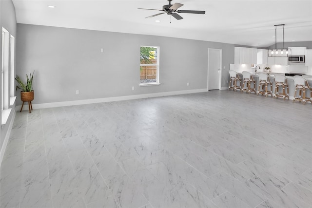 unfurnished living room with sink and ceiling fan with notable chandelier