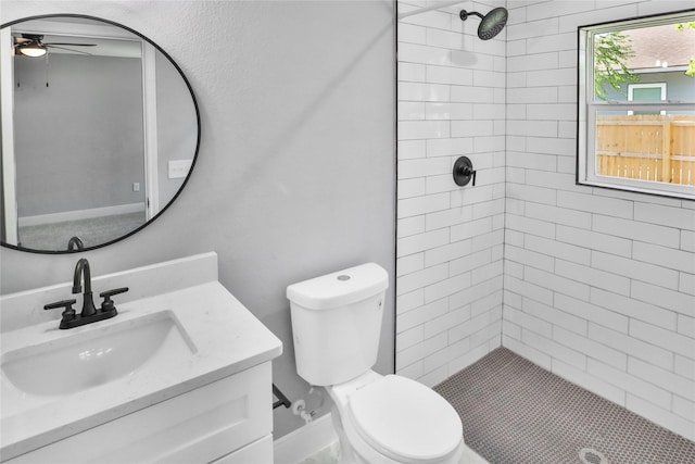 bathroom featuring ceiling fan, tiled shower, vanity, and toilet