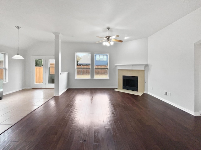 unfurnished living room with ornate columns, dark hardwood / wood-style floors, and ceiling fan