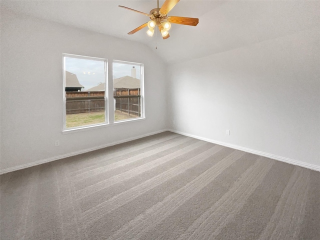 spare room with ceiling fan, vaulted ceiling, and carpet