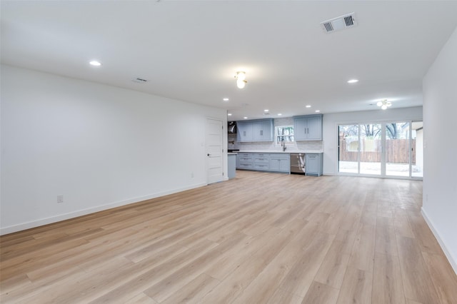 unfurnished living room featuring sink and light wood-type flooring