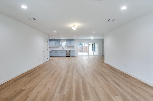 unfurnished living room featuring sink and light hardwood / wood-style floors