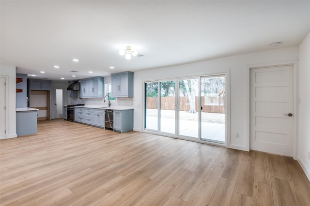 kitchen with dishwasher, sink, decorative backsplash, stainless steel gas range oven, and light wood-type flooring