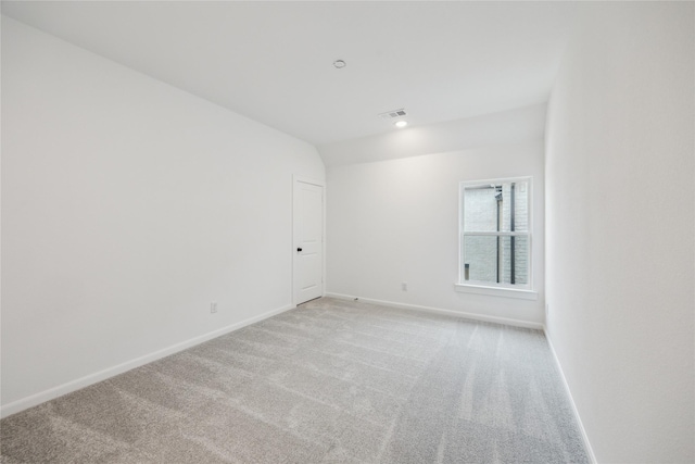 carpeted spare room with vaulted ceiling