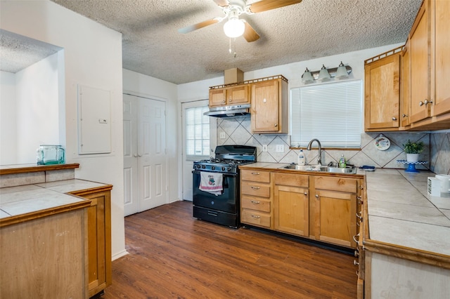 kitchen featuring sink, tile countertops, black gas range oven, dark hardwood / wood-style floors, and backsplash