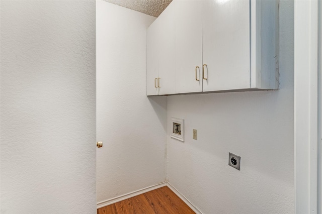 washroom featuring electric dryer hookup, washer hookup, hardwood / wood-style flooring, and cabinets