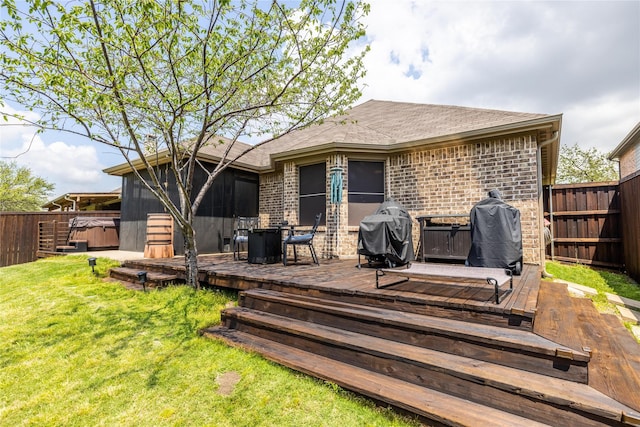 rear view of property with a sunroom, a hot tub, a deck, and a lawn