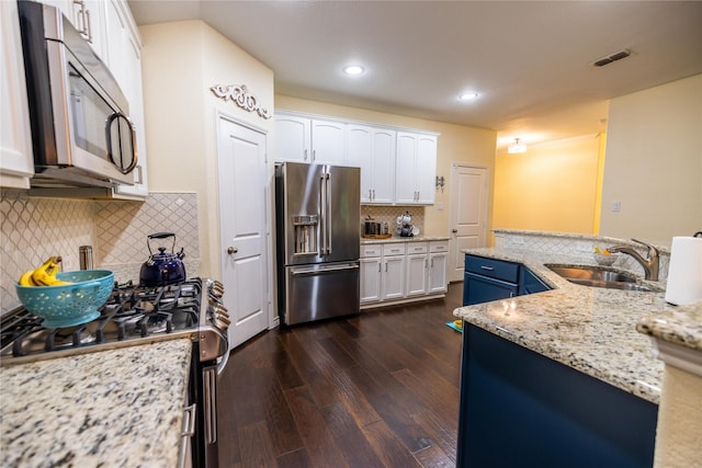 kitchen with sink, stainless steel appliances, light stone countertops, white cabinets, and blue cabinets