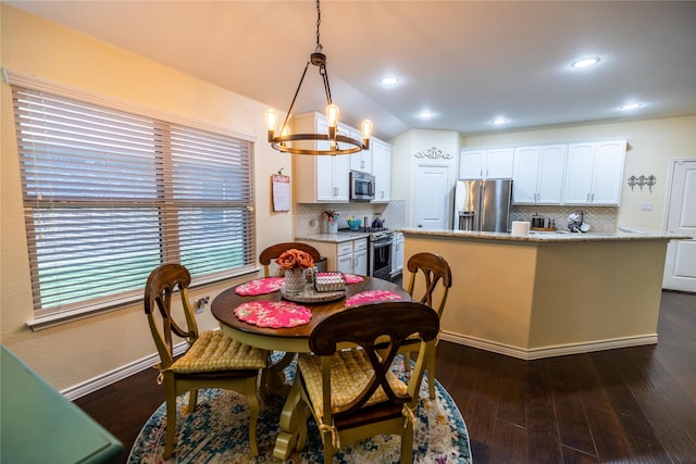 dining space with an inviting chandelier, dark hardwood / wood-style floors, and vaulted ceiling