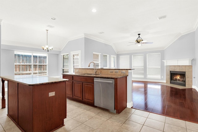 kitchen featuring vaulted ceiling, pendant lighting, sink, a kitchen island with sink, and stainless steel dishwasher