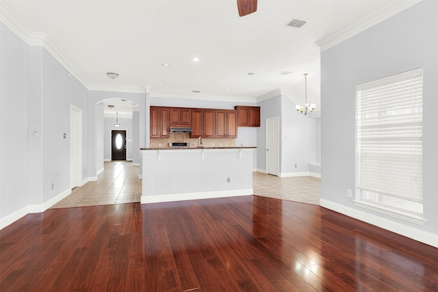 unfurnished living room featuring ornamental molding, sink, ceiling fan with notable chandelier, and light hardwood / wood-style floors