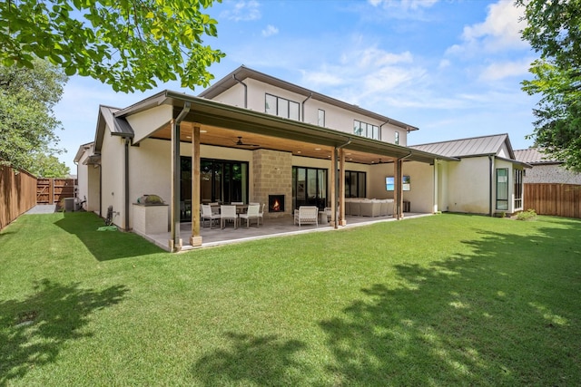 rear view of house featuring ceiling fan, a patio, and a lawn