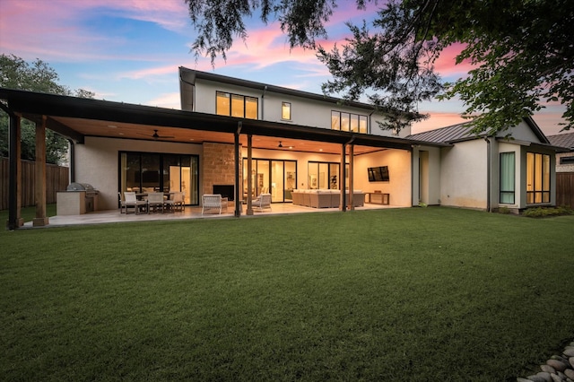 back house at dusk featuring a yard, outdoor lounge area, a patio, and ceiling fan