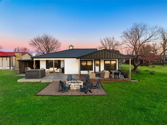 back house at dusk with a patio, a yard, and an outdoor living space with a fire pit