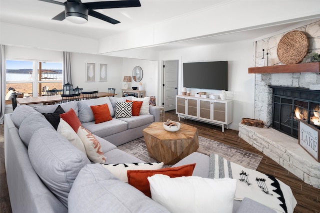 living room featuring wood-type flooring, a stone fireplace, and ceiling fan