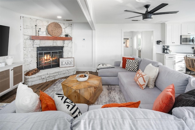 living room with dark wood-type flooring, a fireplace, and ceiling fan