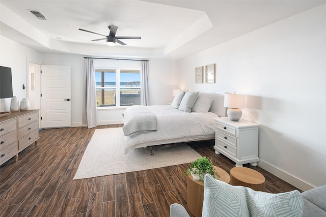 bedroom featuring dark wood-type flooring, ceiling fan, and a tray ceiling