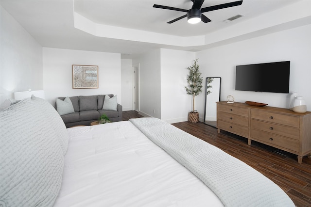 bedroom featuring dark hardwood / wood-style floors, ceiling fan, and a tray ceiling