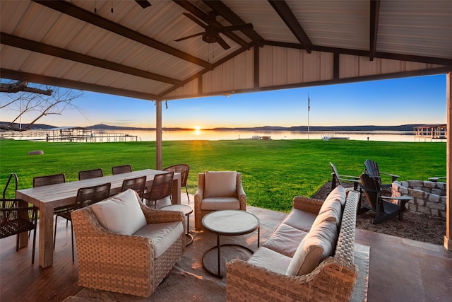 patio terrace at dusk featuring a water view, a gazebo, a yard, outdoor lounge area, and ceiling fan