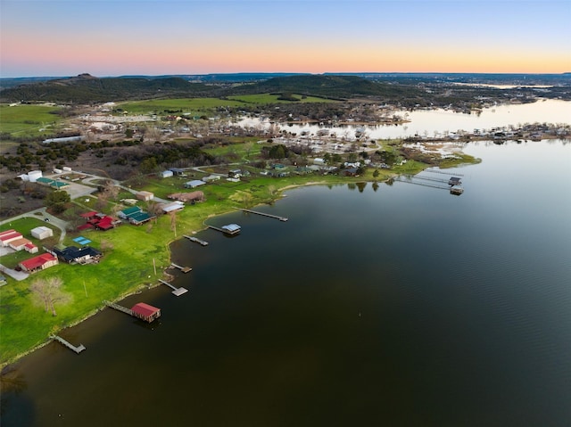 aerial view at dusk featuring a water view