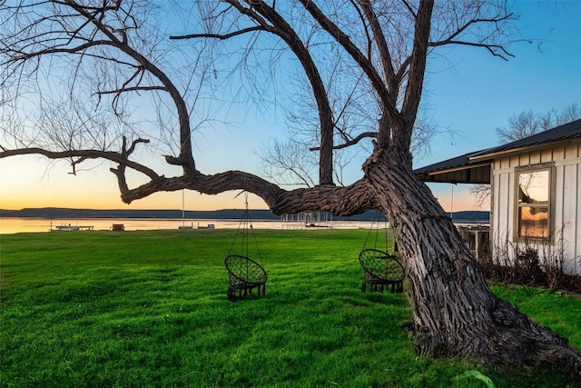 yard at dusk featuring a water view