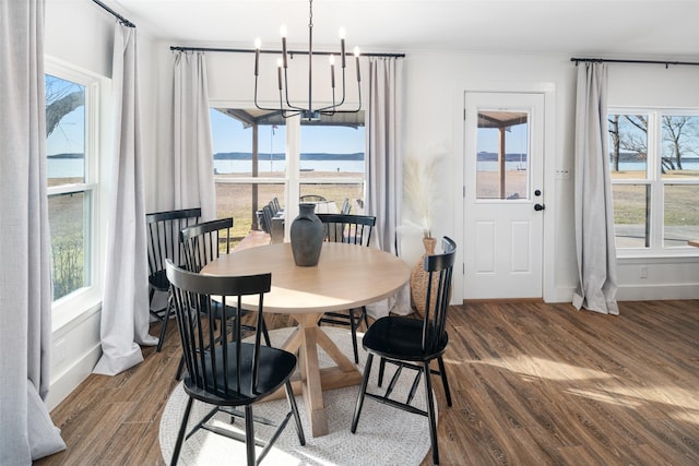 dining room with a water view, wood-type flooring, a chandelier, and a wealth of natural light