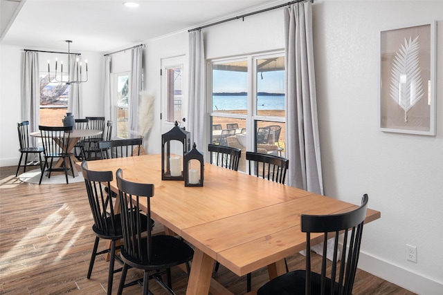 dining space with a water view, hardwood / wood-style floors, and a notable chandelier