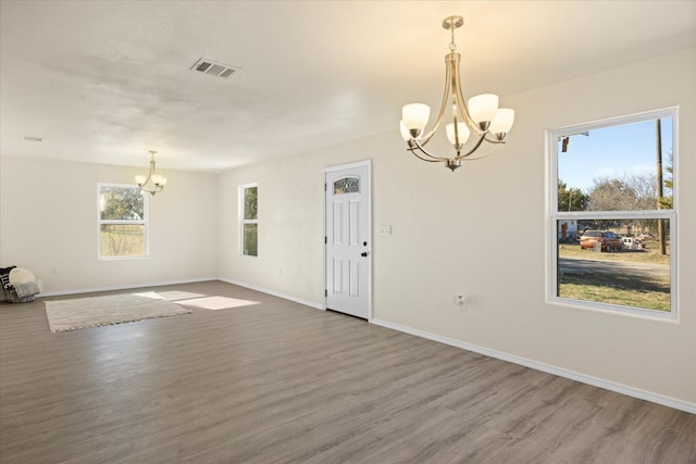 unfurnished room with hardwood / wood-style flooring and a chandelier