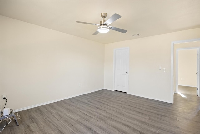 empty room with ceiling fan and dark hardwood / wood-style flooring