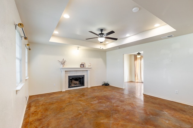 unfurnished living room with a raised ceiling, a tile fireplace, and ceiling fan