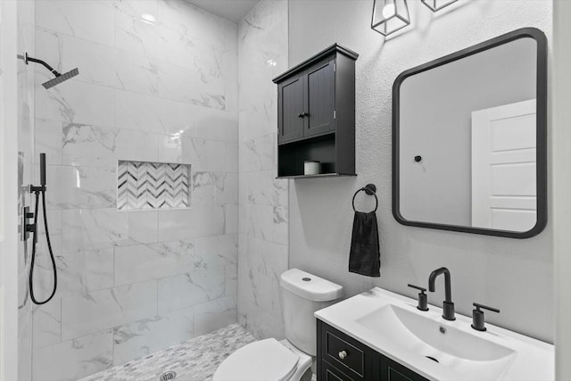 bathroom with vanity, toilet, and tiled shower