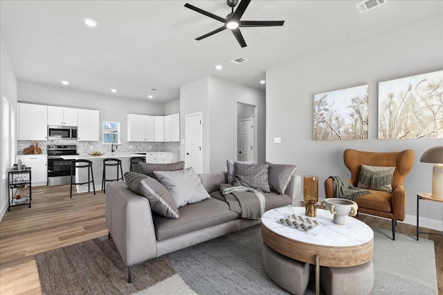 living room with ceiling fan and light hardwood / wood-style floors