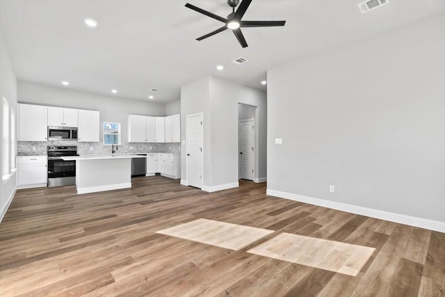 kitchen with a center island, light wood-type flooring, appliances with stainless steel finishes, ceiling fan, and white cabinets