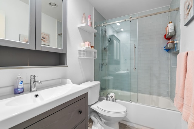 full bathroom with vanity, bath / shower combo with glass door, and toilet