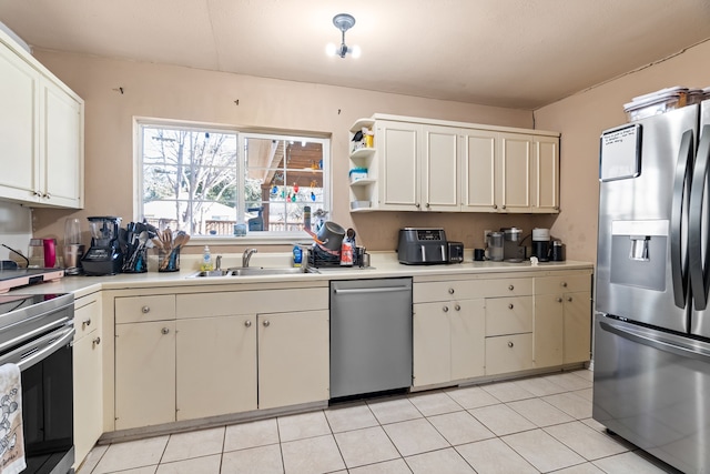 kitchen featuring light tile patterned flooring, white cabinetry, appliances with stainless steel finishes, and sink