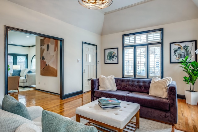 living room with hardwood / wood-style flooring, vaulted ceiling, and ornamental molding